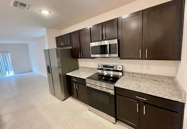 a kitchen with stainless steel appliances a stove microwave and refrigerator