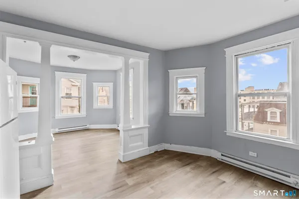 a view of an empty room with wooden floor and a window