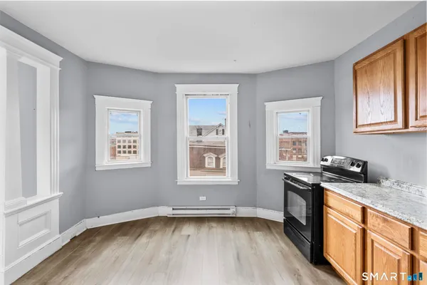 a view of a kitchen and an empty room with wooden floor windows