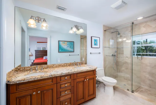 a bathroom with a granite countertop sink a toilet a mirror and shower