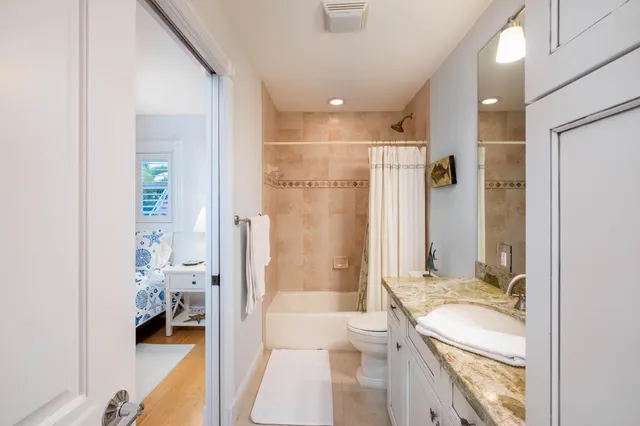 a bathroom with a granite countertop sink a toilet and shower