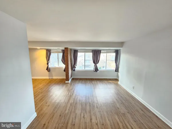 an empty room with wooden floor and windows