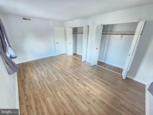 a view of empty room with wooden floor and window