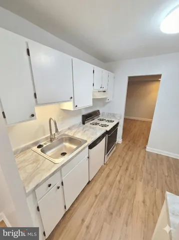 a kitchen with granite countertop a sink stove and cabinets