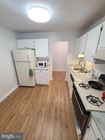 a kitchen with stove a refrigerator and a stove with wooden floor