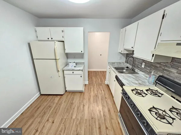 a kitchen with a stove a refrigerator and a wooden floor