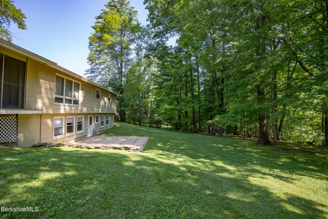 a view of a house with a big yard potted plants and large tree