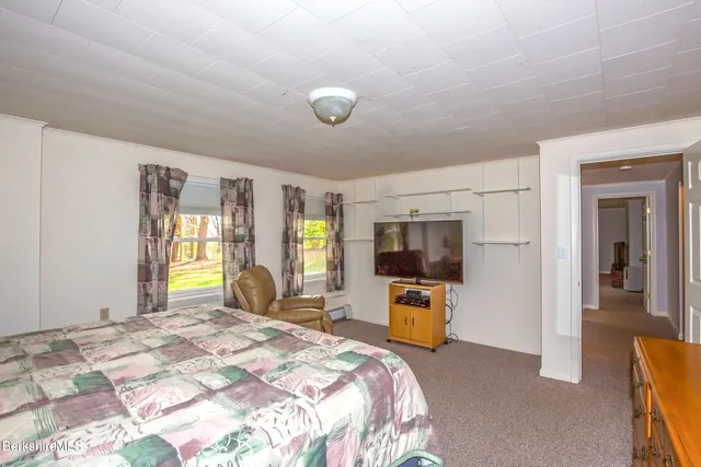 a bedroom with a bed and a flat tv screen next to a large window