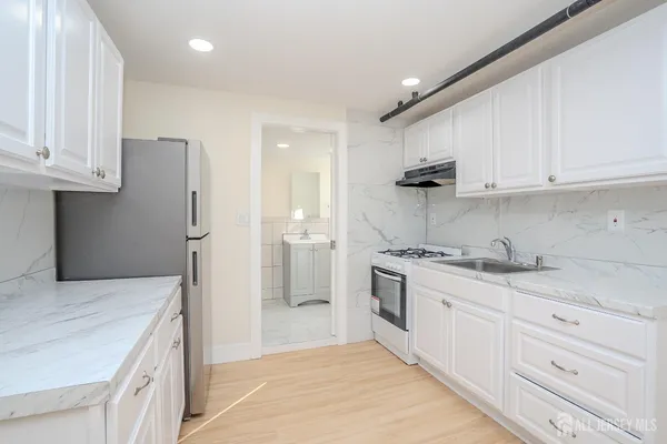 a kitchen with granite countertop a sink stove and refrigerator