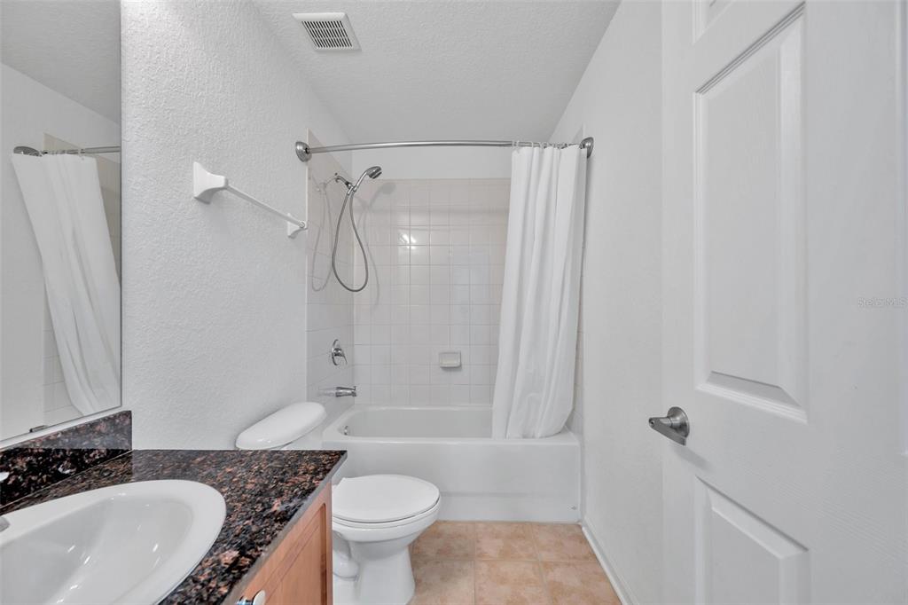 8206 Bally Money Road Tampa, FL 33610 - Photo 26 of 43 a bathroom with a granite countertop sink toilet a shower and a mirror
