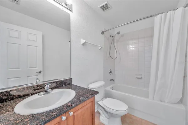 a bathroom with a granite countertop sink a toilet and a bathtub