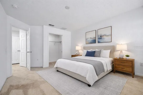 a spacious bedroom with a bed and a lamp