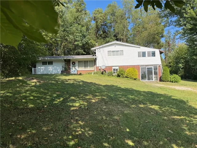 a front view of house with yard and trees in the background