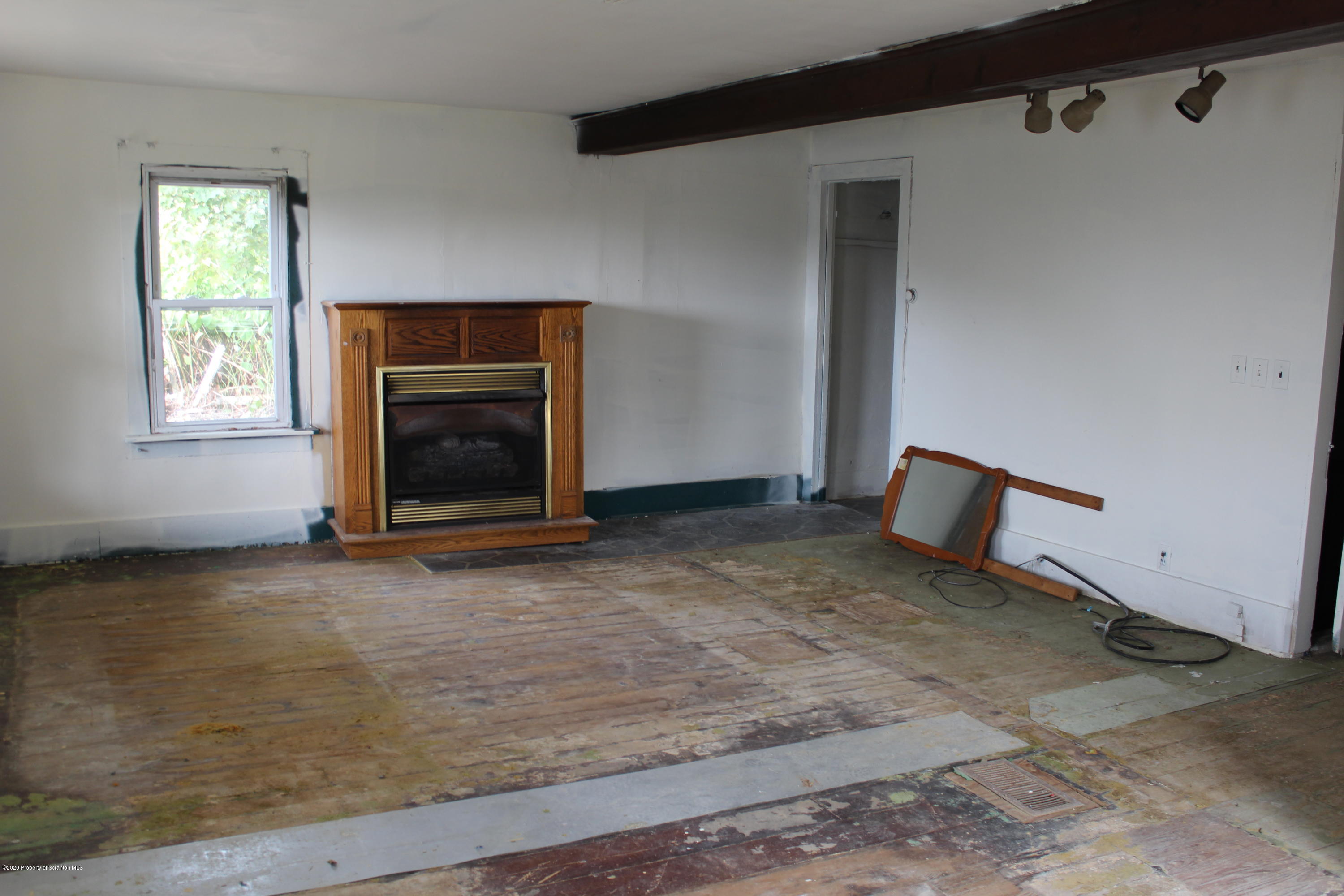 87 Academy Street Springville, PA 18844 - Photo 8 of 23 a view of an empty room with a fireplace and a window