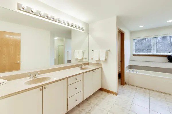 a spacious bathroom with a double vanity sink a mirror and a bathtub