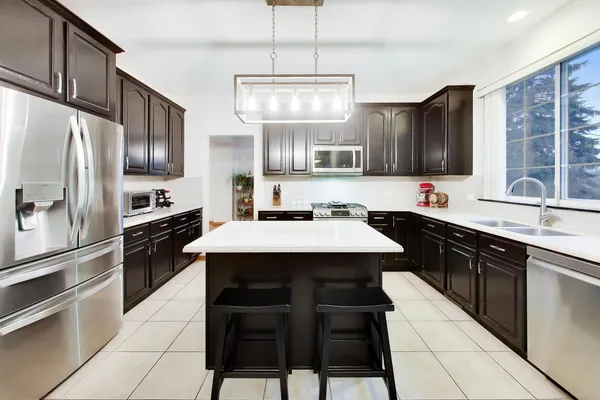 a kitchen with stainless steel appliances kitchen island granite countertop a sink stove and refrigerator