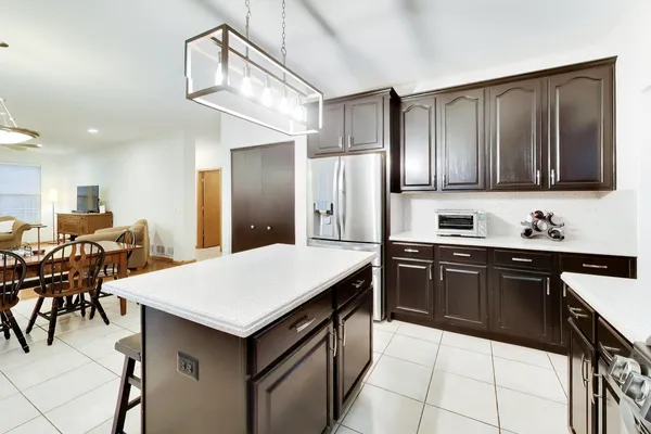 a kitchen with a stove a sink a kitchen island with chairs and wooden cabinets