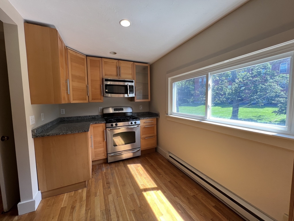 76 Chestnut Street, Unit 2 Newton, MA 02465 - Photo 2 of 21 a kitchen with granite countertop a stove a sink and a microwave
