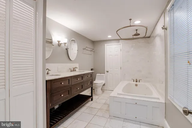 a bathroom with a double vanity sink mirror and bathtub