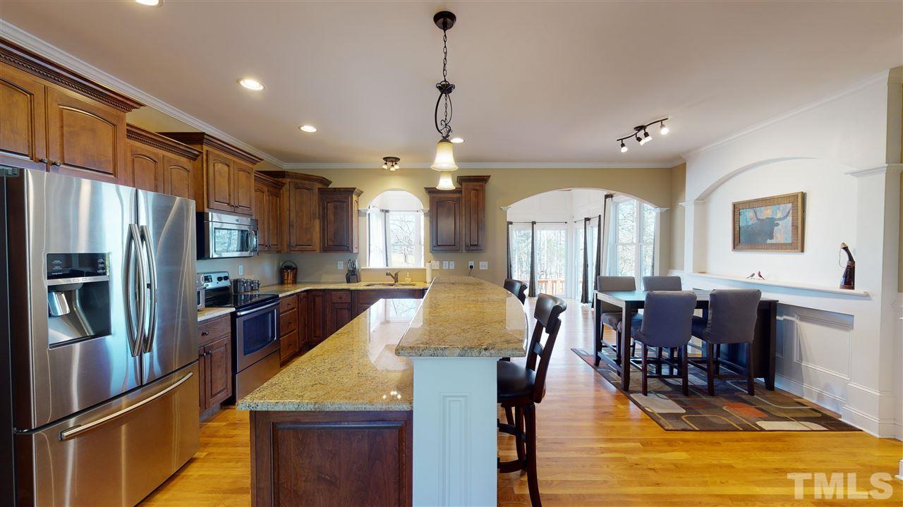 3537 Saddle Ridge Road Stem, NC 27581 - Photo 11 of 29 a large kitchen with stainless steel appliances granite countertop a stove refrigerator a dining table and chairs with wooden floor