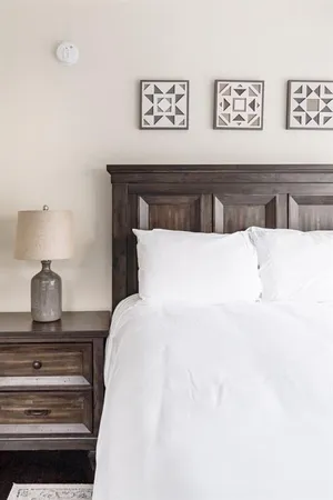 a bedroom with a bed and a lamp on dresser
