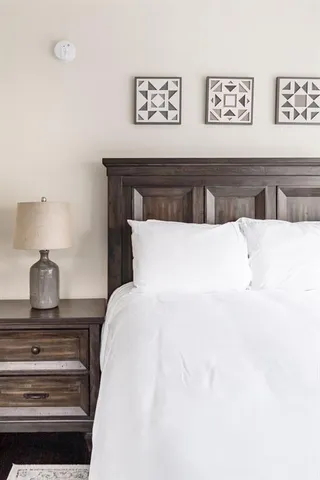 a bedroom with a bed and a lamp on dresser