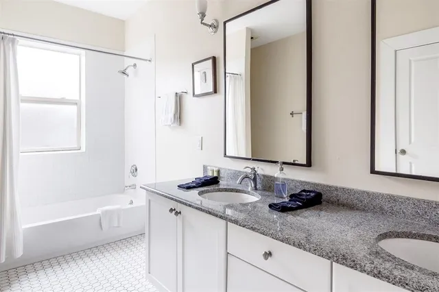 a bathroom with a granite countertop sink and a mirror a bathtub