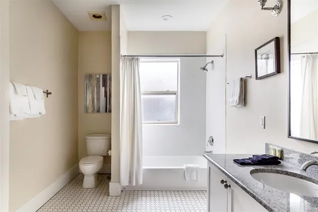 a bathroom with a granite countertop sink a toilet and shower