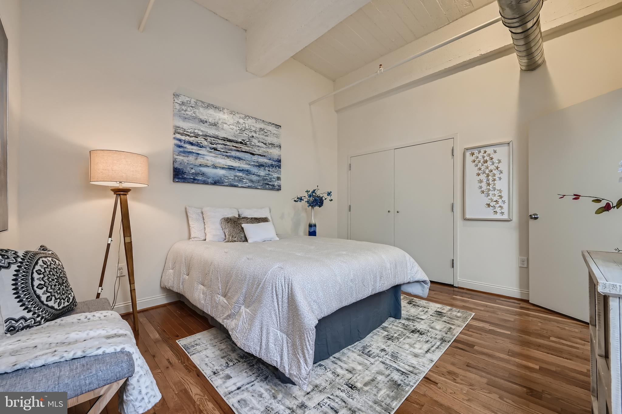 311 West Baltimore Street, Unit 501 Baltimore, MD 21201 - Photo 11 of 28 a bedroom with a bed lamp and a dresser