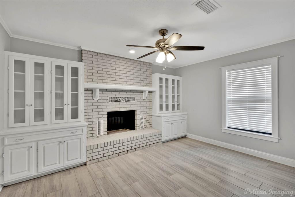 8344 Odom Road Greenwood, LA 71033 - Photo 24 of 39 Unfurnished living room featuring ceiling fan, light wood-type flooring, ornamental molding, and a brick fireplace