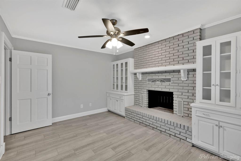 8344 Odom Road Greenwood, LA 71033 - Photo 25 of 39 Unfurnished living room with a ceiling fan, light wood-style floors, ornamental molding, a brick fireplace, and recessed lighting