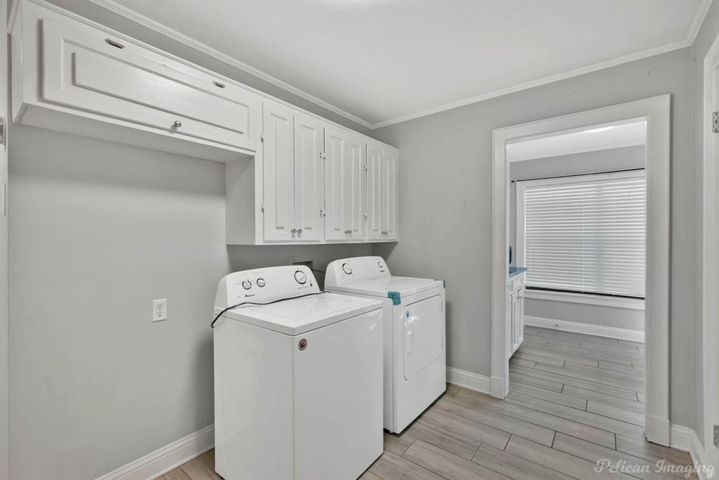 8344 Odom Road Greenwood, LA 71033 - Photo 26 of 39 Laundry area featuring washing machine and clothes dryer, light wood-type flooring, ornamental molding, and cabinet space