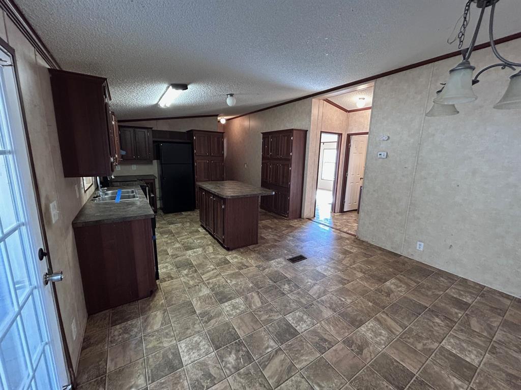 329 Canvas Back Drive Princeton, LA 71067 - Photo 14 of 20 Kitchen featuring dark countertops, dark wood finish cabinets, a kitchen island, and ornamental molding