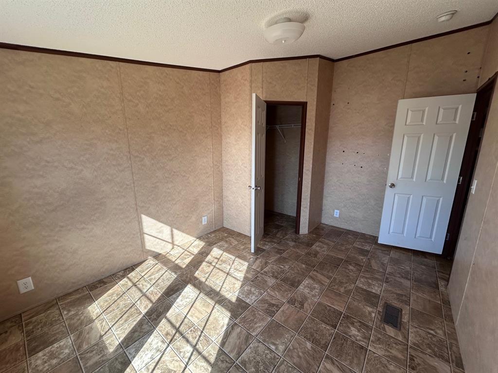 329 Canvas Back Drive Princeton, LA 71067 - Photo 15 of 20 Unfurnished bedroom with crown molding, a textured ceiling, dark stone finish floors, and a closet