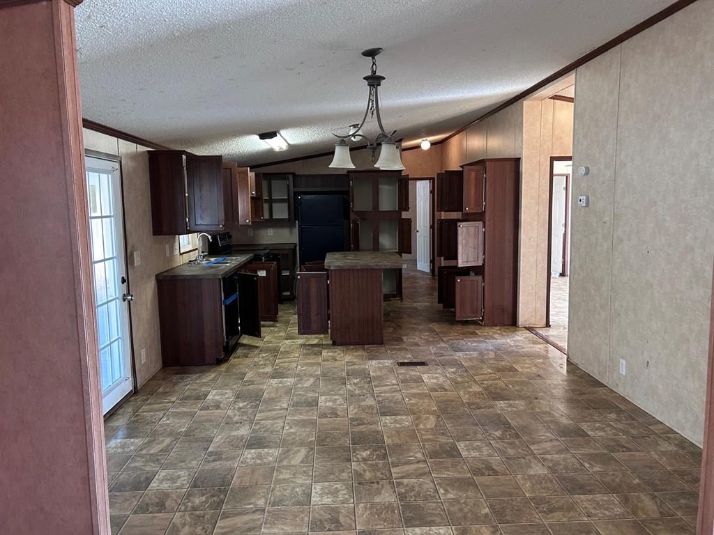 329 Canvas Back Drive Princeton, LA 71067 - Photo 8 of 20 Kitchen featuring dark wood finish cabinetry, a kitchen island, dark countertops, decorative light fixtures, and stone finish flooring