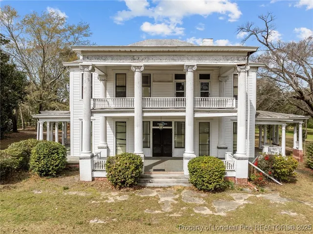 a view of a brick house with potted plants and large trees