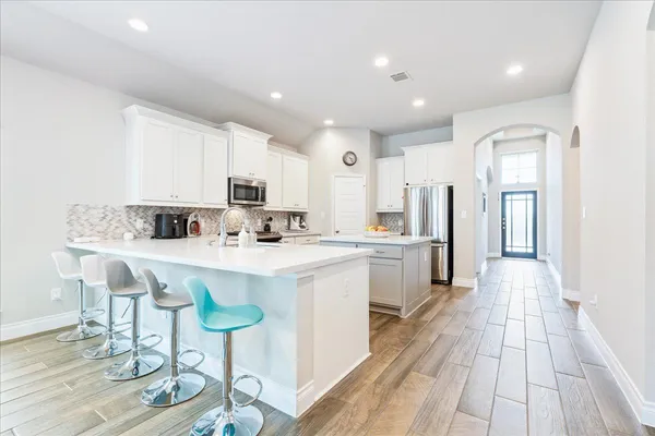a kitchen with stainless steel appliances a sink a stove a refrigerator cabinets and a dining table