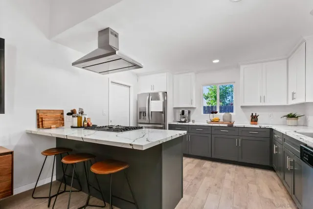 a kitchen with stainless steel appliances granite countertop a sink a stove and chairs