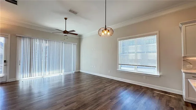 an empty room with wooden floor chandelier and windows