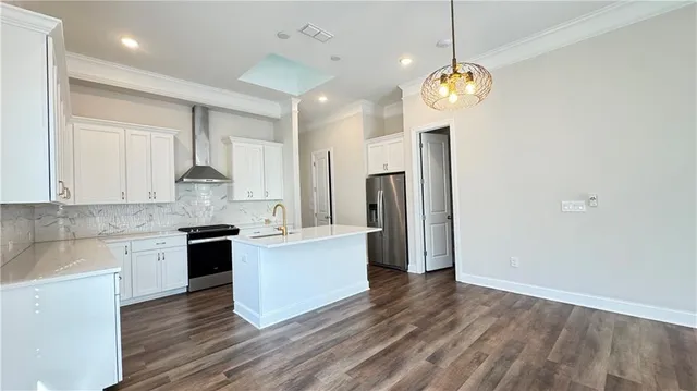 a kitchen with stainless steel appliances granite countertop a refrigerator a sink dishwasher a stove and white countertops with wooden floor