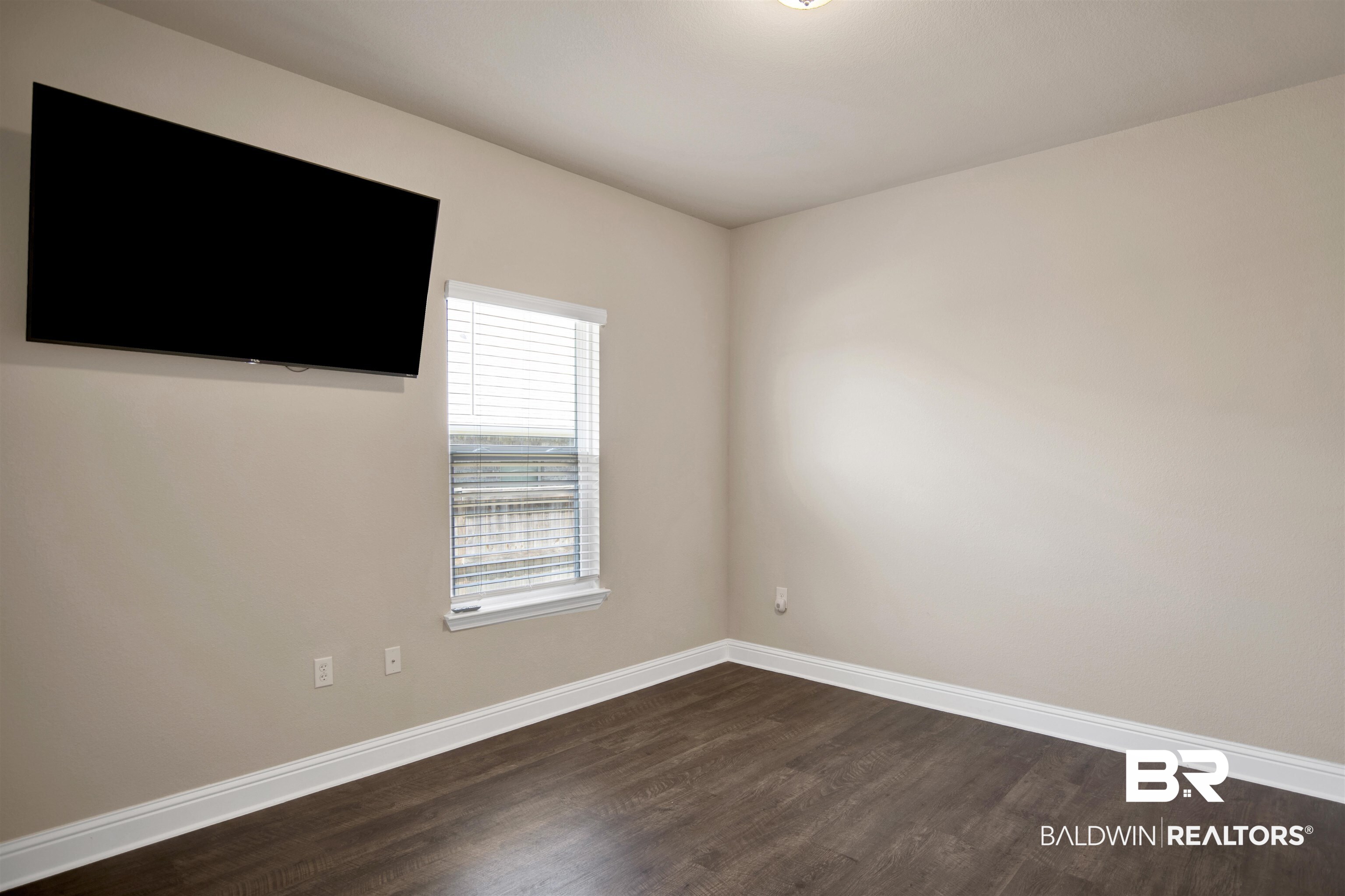 8493 Bronze Lane Foley, AL 36535 - Photo 28 of 38 Neutral-toned walls complement wood-finish flooring in this room featuring a window with horizontal blinds