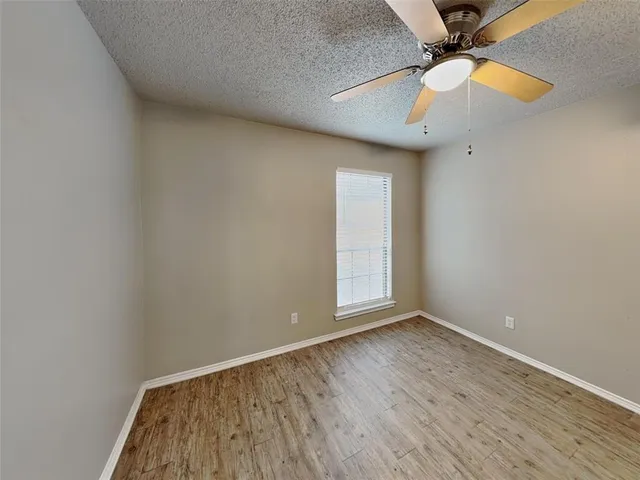 an empty room with a window and wooden floor