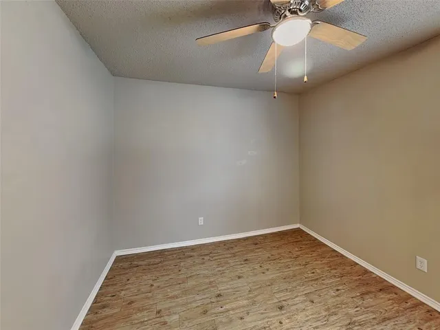 en empty room with wooden floor and fan
