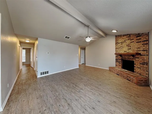 an empty room with wooden floor and fireplace