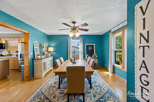 a dining hall with stainless steel appliances granite countertop a stove top oven a dining table and chairs with wooden floor