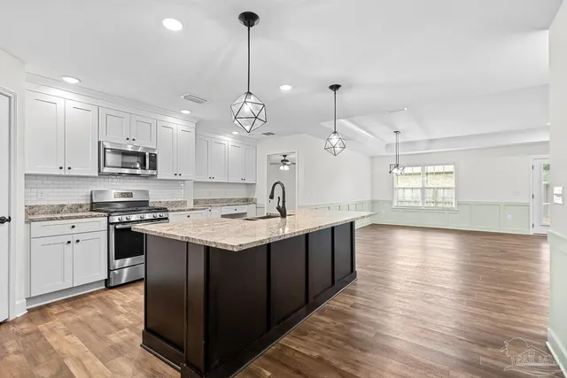 a kitchen with stainless steel appliances granite countertop a sink a stove and a refrigerator