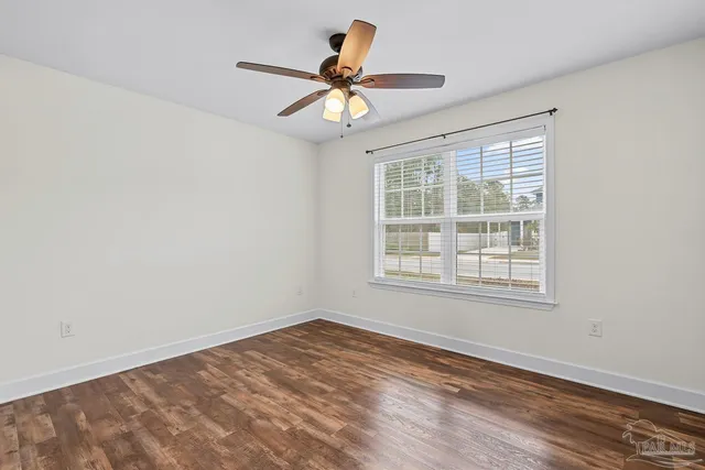 an empty room with wooden floor closet and fan