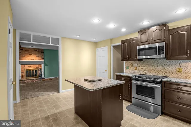 a kitchen with stainless steel appliances granite countertop a stove a sink and a microwave