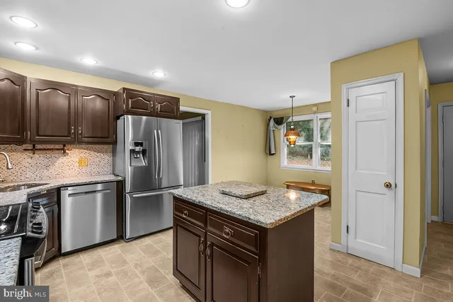 a kitchen with granite countertop kitchen island stainless steel appliances a refrigerator sink and stove