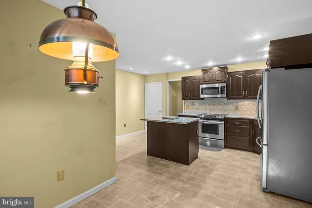 a kitchen with stainless steel appliances granite countertop a sink a stove and a refrigerator